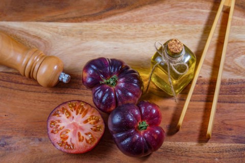 Top view of a group of tasty fresh tomatoes of the blue variety next to some wooden tongs, olive