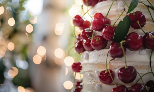Ripe cherries adorning a wedding cake, closeup view, bokeh lights on background AI generated