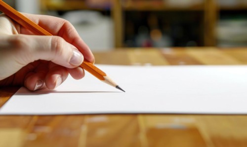 A hand holding a graphite pencil poised over a blank sheet of white paper AI generated