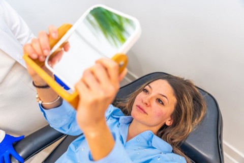 Adult caucasian woman lying on stretcher in a beautician clinic looking herself after apply