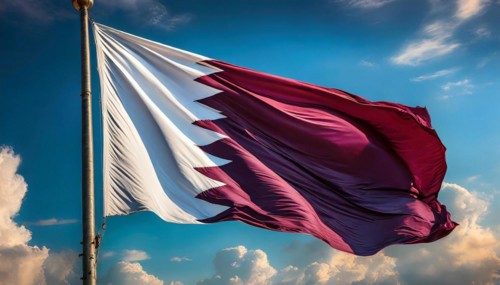The flag of Qatar flutters in the wind, isolated against a blue sky