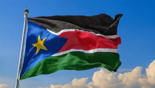 The flag of South Sudan, fluttering in the wind, isolated, against the blue sky