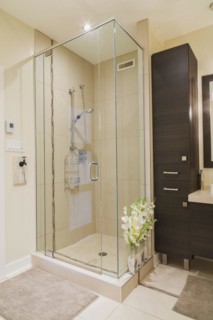 Contemporary brown laminated wood vanity and clear glass shower stall in bathroom inside a