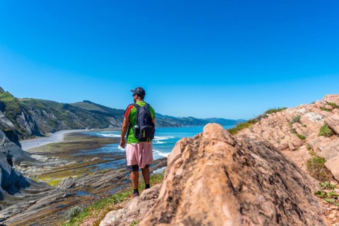 A male hiker in Algorri cove on the coast in the flysch of Zumaia, Gipuzkoa. Basque Country