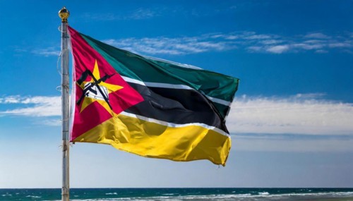 The flag of Mozambique, fluttering in the wind, isolated, against the blue sky