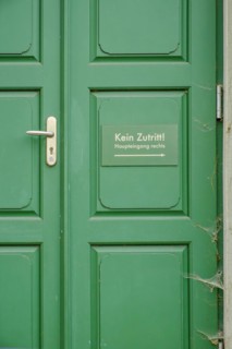 No entry, main entrance on the right, sign on a green front door in the historic city centre of