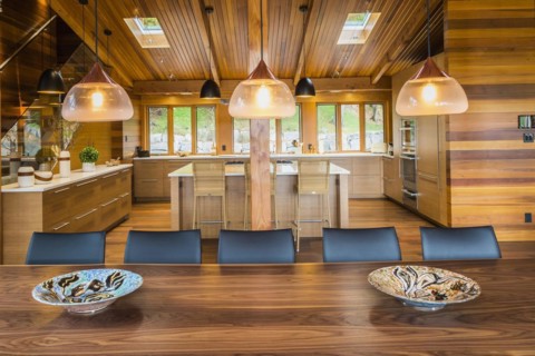 Illuminated industrial style copper with frosted glass pendant lighting fixtures over wooden dining