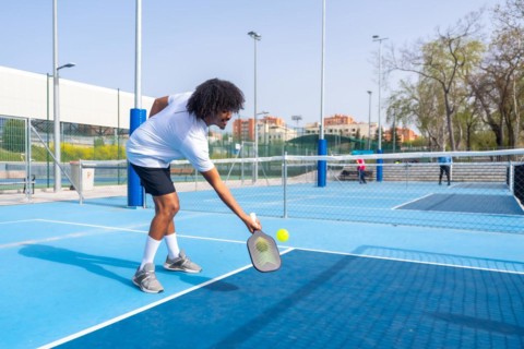 Full length photo of two african american young male friends playing pickleball together in an