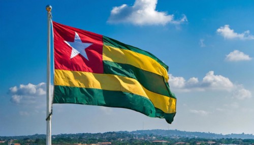The flag of Togo flutters in the wind, isolated against a blue sky