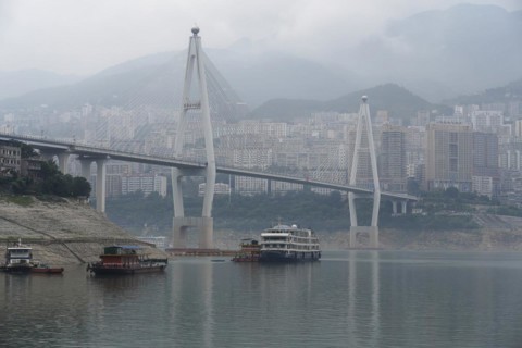 Chongqing, Chongqing Province, Modern bridge over a river with light fog, cityscape behind,
