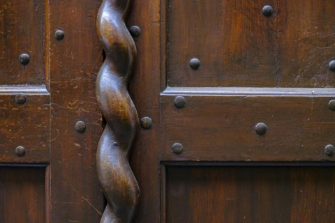 Application on wood, antiquated door fitting in the form of a spiral bar on a historic front door,