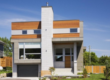 Two story grey and charcoal stone with cedar wood siding modern cube style home facade in summer,