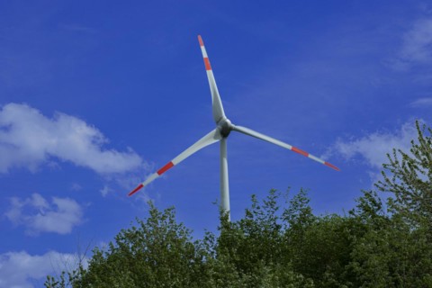 Wind turbine behind green trees at the Avacon substation Helmstedt, Helmstedt, Lower Saxony,