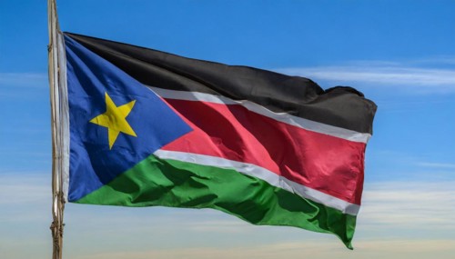 The flag of South Sudan, fluttering in the wind, isolated, against the blue sky