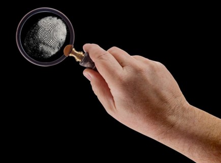 Male hand holding magnifying glass viewing A fingerprint on a black background