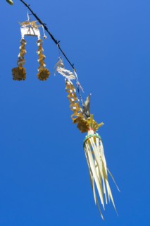 Ornate jewellery woven from palm leaves on bamboo poles, on a village street in Amed, Karangasem,