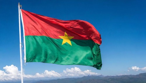 The flag of Burkina Faso flutters in the wind, isolated against the blue sky