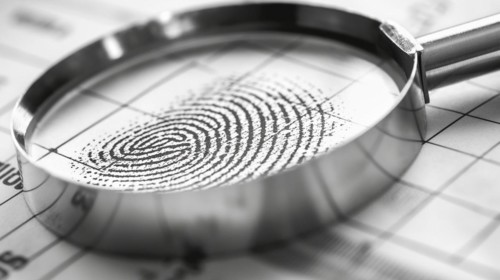 Magnifying glass resting on a fingerprint on paper. generative AI, AI generated