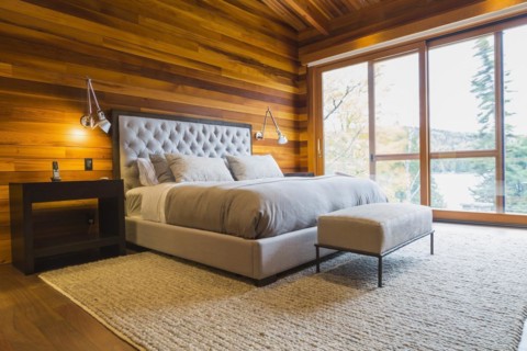 King size bed with grey upholstered panel headboard, ottoman and wooden end tables in master