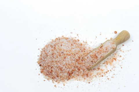 Top view of a wooden spoon with pink Himalayan salt isolated on white background and copy space