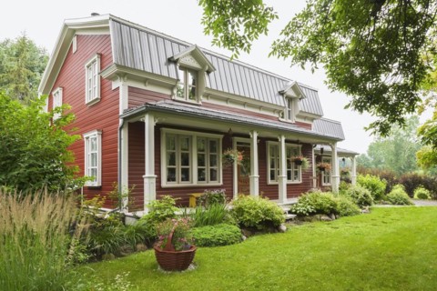 Old 1892 burgundy with white trim pinewood plank house facade with mansarde style grey sheet metal