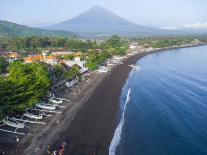 Fishermen unload their catch from their outrigger boat in the morning, in the background Gunung