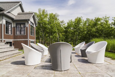 White and grey cloth covered sitting chairs on backyard patio and rear view of contemporary natural