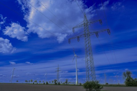 Power pylons with high-voltage lines and wind turbines on the K63 road with trees at the Avacon