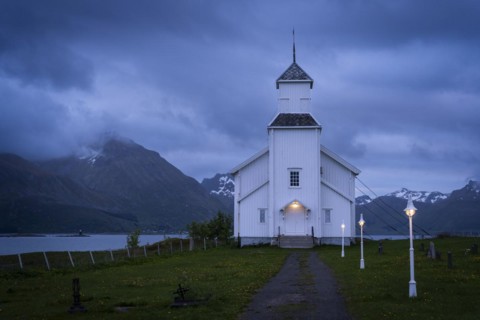 The white church of Gimsoy (Gimsoysand church) by the sea. A path leads to the church. The church