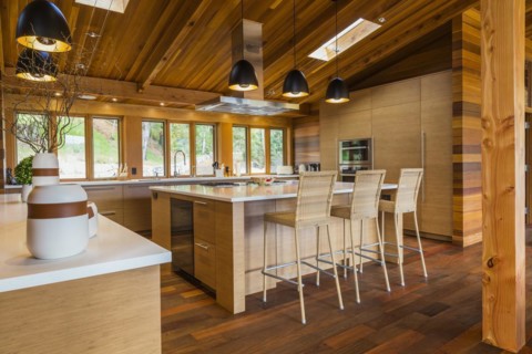 Bamboo wood buffet and island with white quartz countertops and high wicker chairs, cabinets in