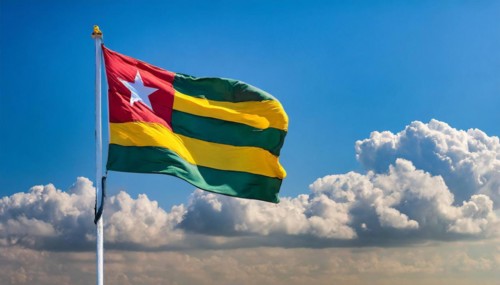 The flag of Togo flutters in the wind, isolated against a blue sky