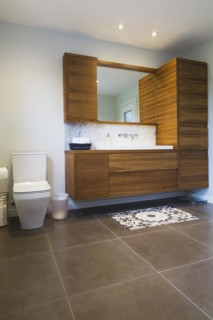 White high-back flush toilet and American walnut wood vanity with white rectangular sink and