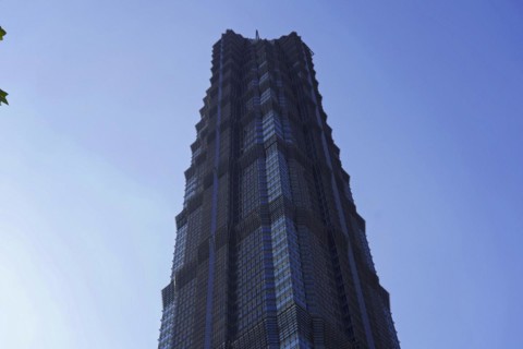 The facade of a geometrically designed skyscraper stands out against the blue sky, Shanghai, China,