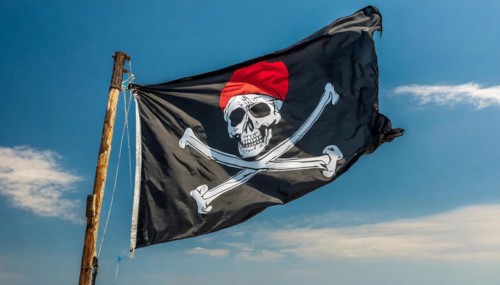 The pirate flag flutters in the wind, isolated against the blue sky