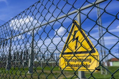Yellow warning sign with the inscription Hochspannung Lebensgefahr! on a fence of the Avacon