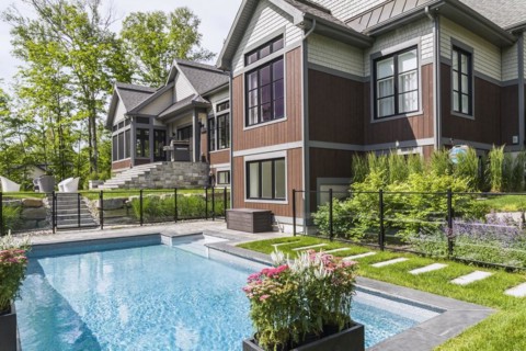 In-ground swimming pool and rear view of contemporary natural stone and brown stained wood and