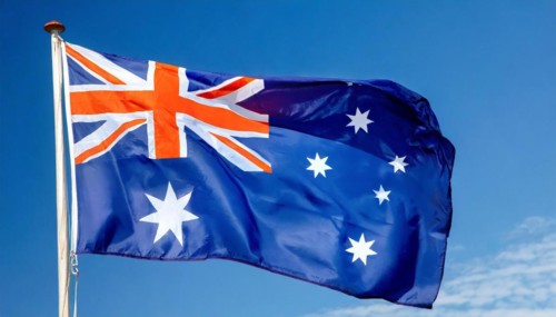 The flag of Australia flutters in the wind, isolated against a blue sky