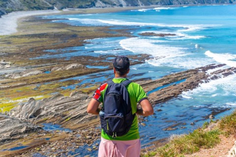 A man with his back turned in Algorri cove on the coast in the flysch of Zumaia, Gipuzkoa. Basque
