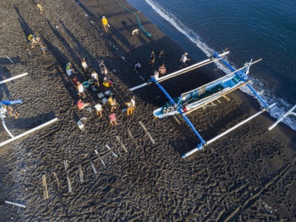 Fishermen unload their catch from their outrigger boat in the morning. Amed, Karangasem, Bali,