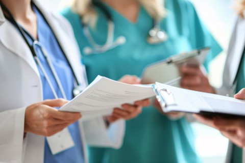Staff meeting between doctors and nurses sharing documents in hospital or clinic. KI generiert,