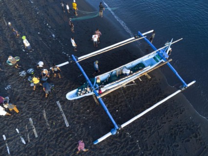 Fishermen unload their catch from their outrigger boat in the morning. Amed, Karangasem, Bali,