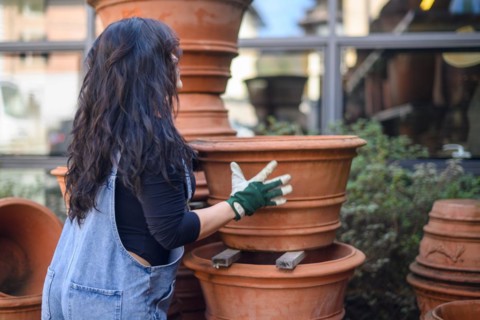 A woman arranging terracotta pots in a workshop setting