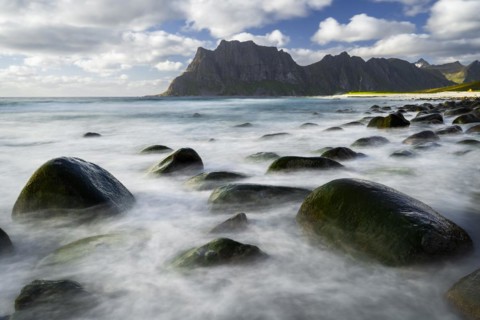 Seascape on the beach at Uttakleiv (Utakleiv) . Rocks in the sea. Round stones surrounded by water.