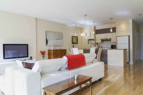 White leather sofa in living room and view of dining room area and kitchen inside a renovated