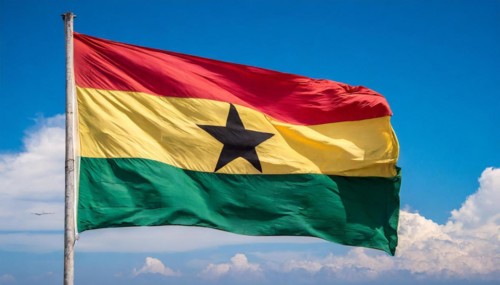 The flag of Ghana flutters in the wind, isolated against a blue sky