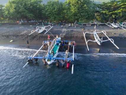 Fishermen unload their catch from their outrigger boat in the morning. Amed, Karangasem, Bali,