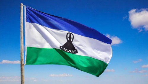 The flag of Lesotho, fluttering in the wind, isolated, against the blue sky