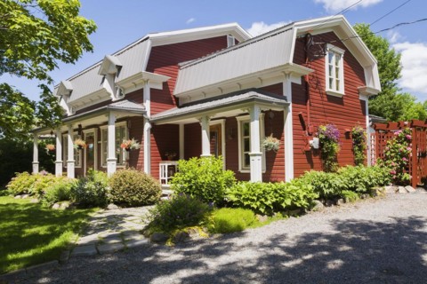Old 1892 burgundy with white trim pinewood plank house facade with mansarde style grey sheet metal