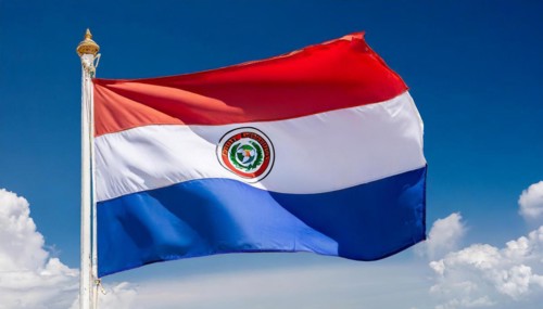 The flag of Paraguay flutters in the wind, isolated against a blue sky
