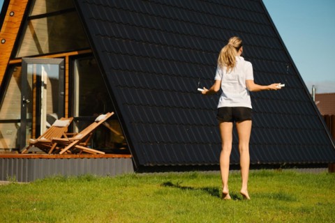 Mid adult a woman jumps with a smart rope on the lawn in front of tiny house